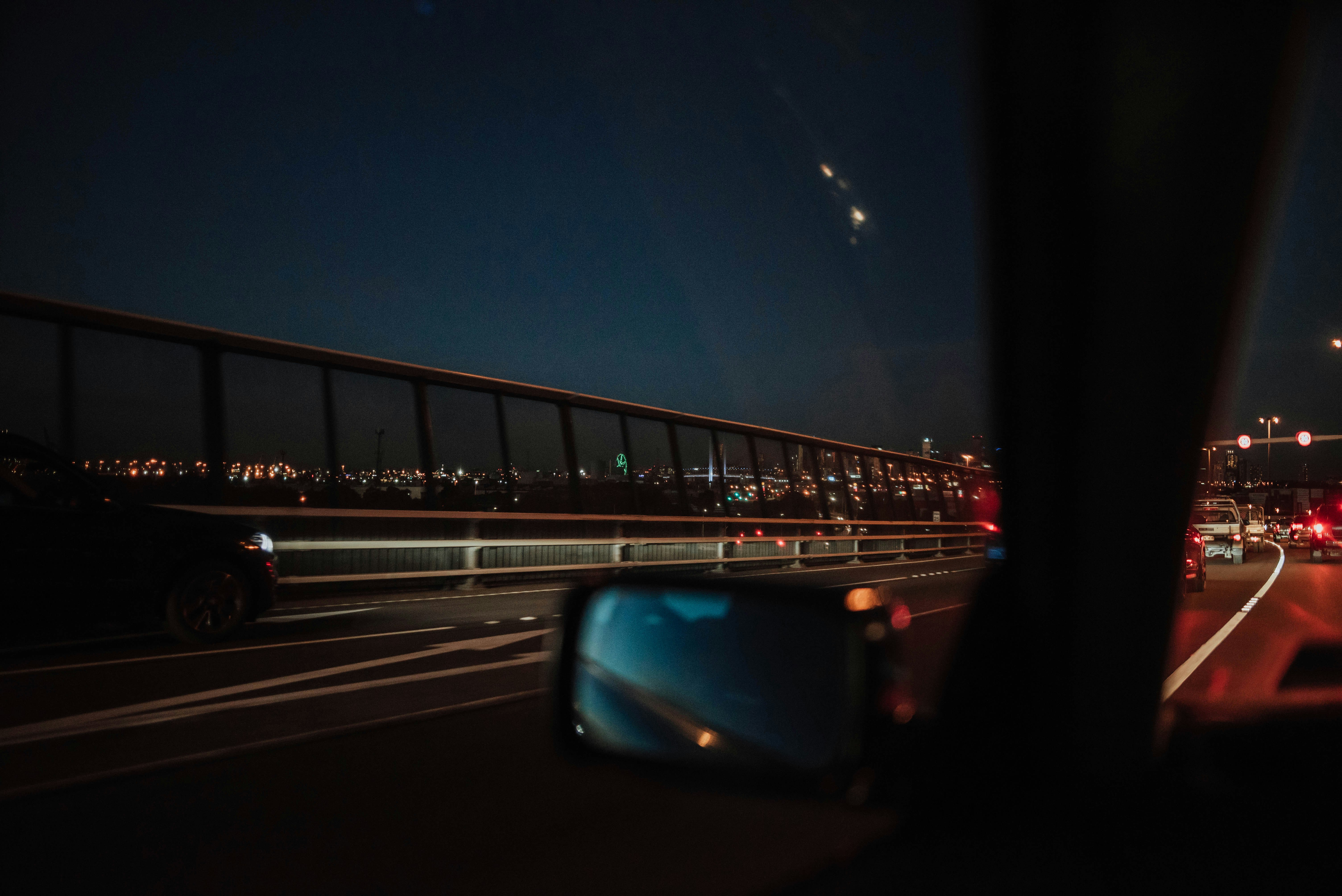 person inside car taking photo on bridge